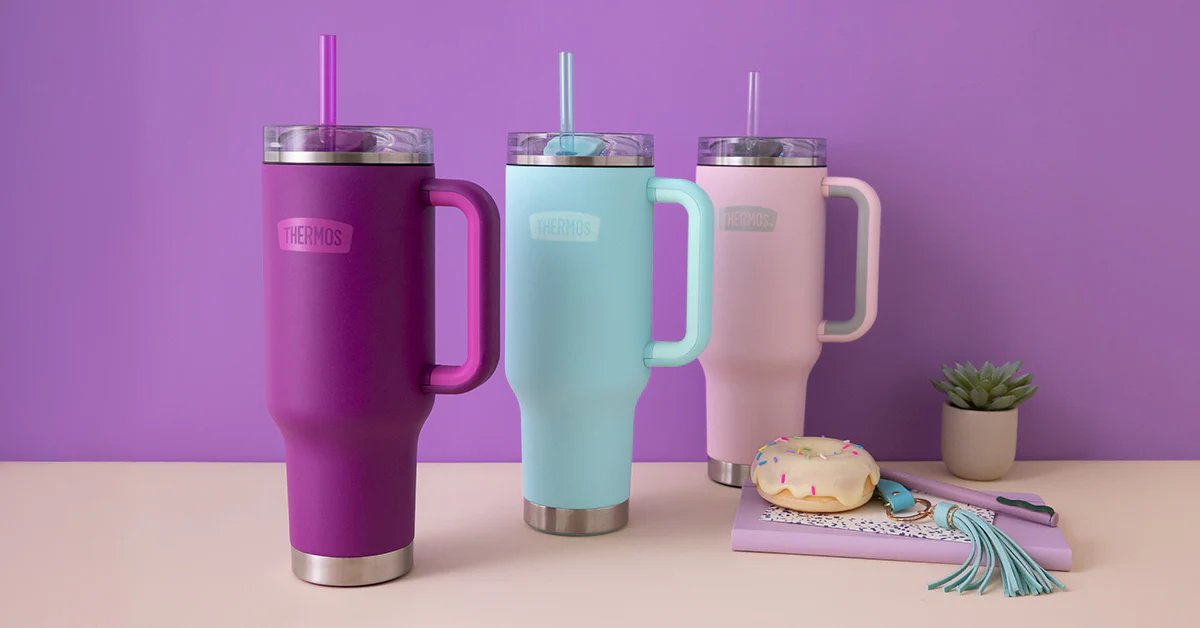 Three insulated 40oz travel mugs in purple, blue, and pink on a table with a purple background.
